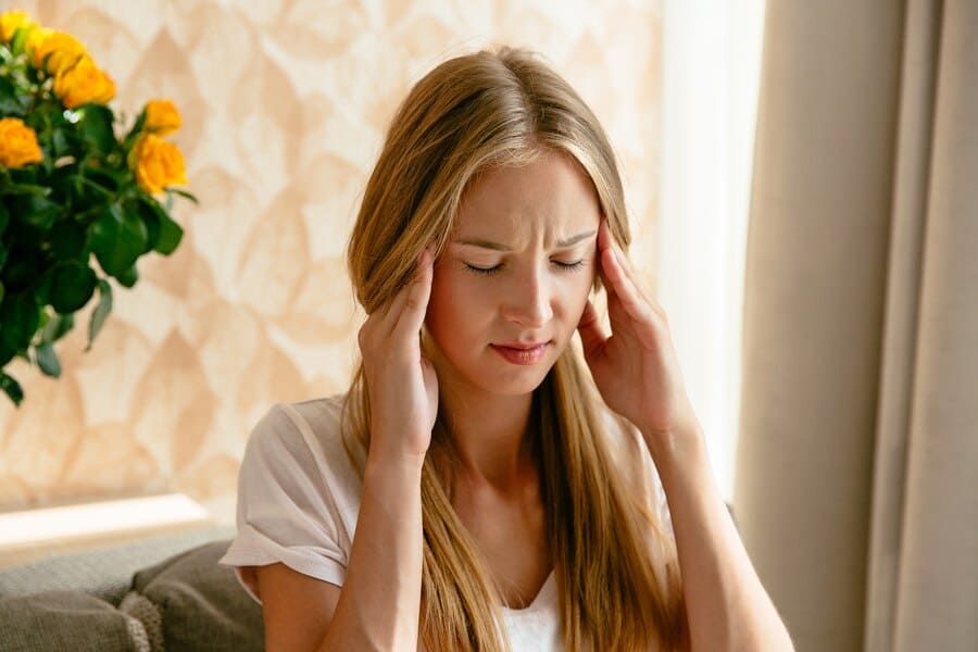 girl holding hands to her temples as if she has a migraine