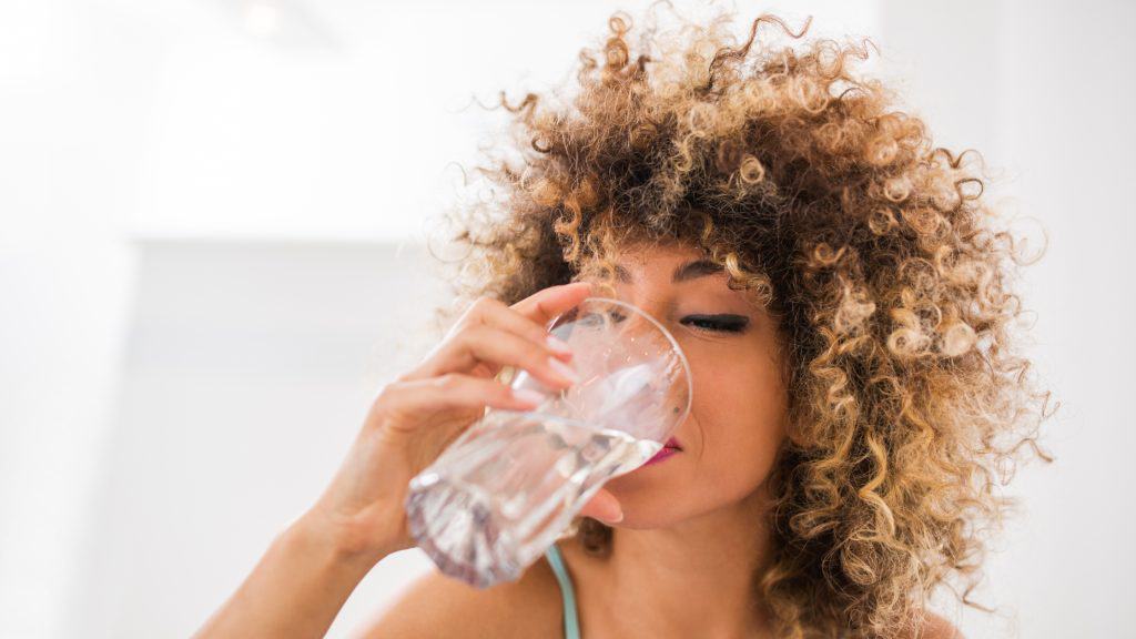 woman drinking water out of a glass