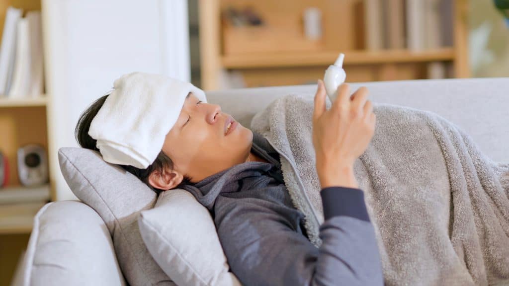 man with fever holding thermometer and reading the temperature